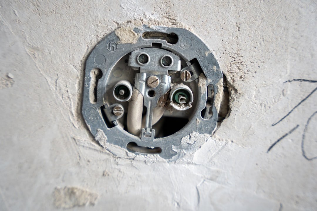 Services A close-up view of an uncovered wall socket during electrical installation, with exposed wires and mounting plate embedded in rough plaster. The image highlights the technical and tactile aspects of renovation work.